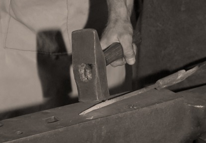 blacksmith works with hammer and anvil