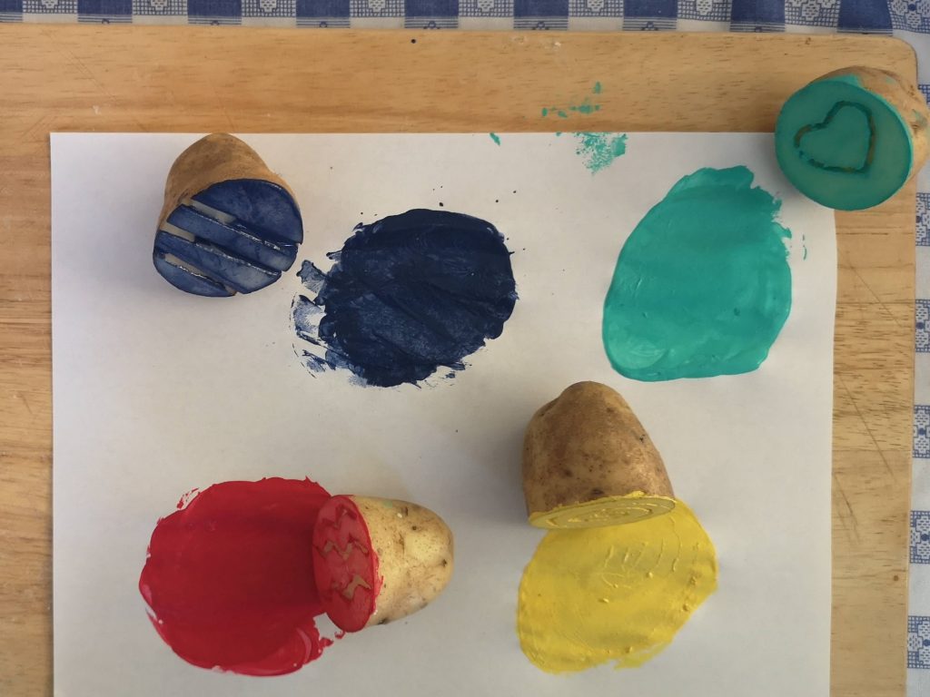 Four potato stamps next to circles of paint