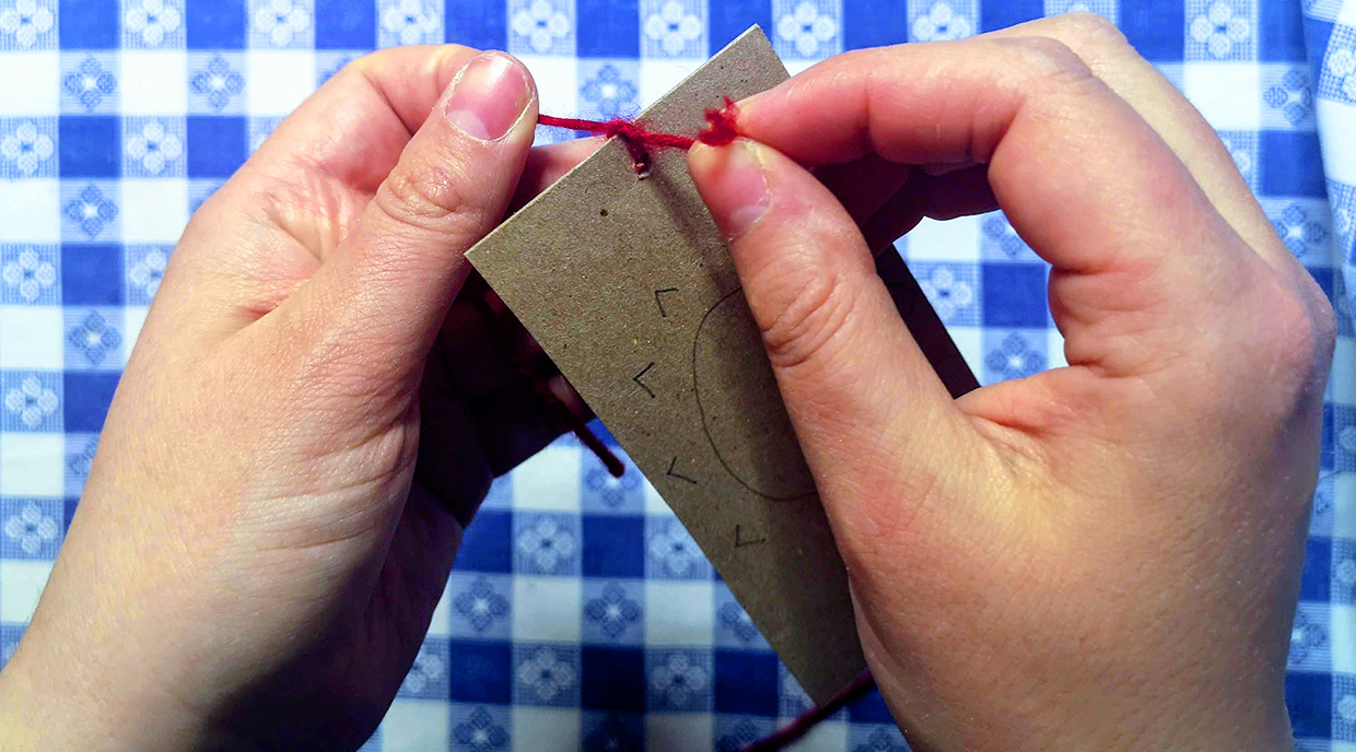 crafter threads string through hole in piece of cardboard to make an optical toy