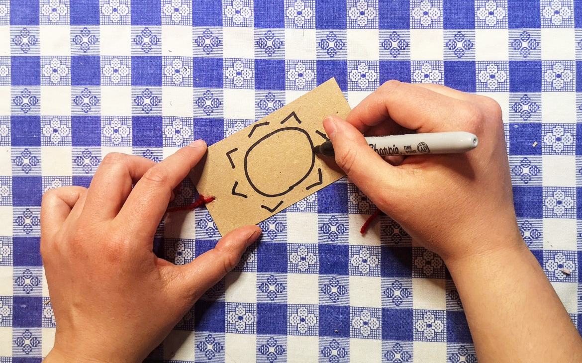 crafter draws picture of the sun on other side of piece of cardboard to make an optical toy