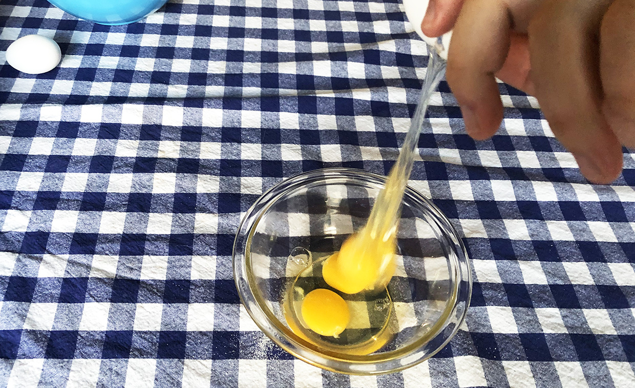 baker cracks eggs into bowl