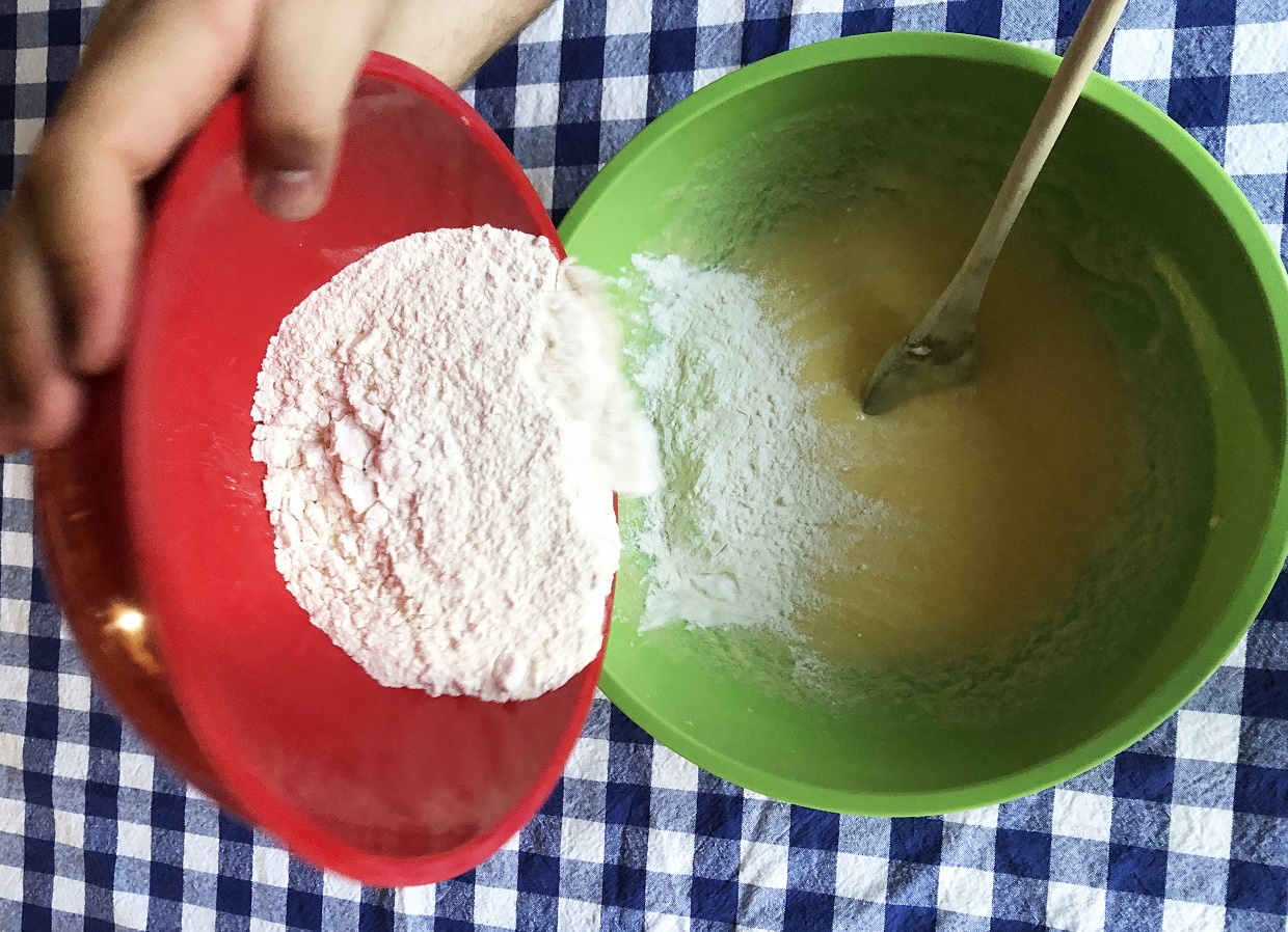 baker adds flour to cup cake mix