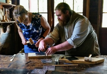 woman learns tinsmithing skills from instructor in DIY Heritage Trades workshop at Black Creek Pioneer Village