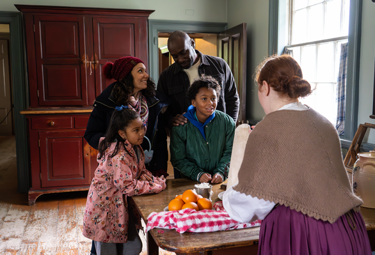 a family interact with an interpreter in the old house kitchen