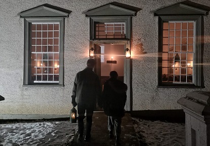 couple approaches village meeting house after dark