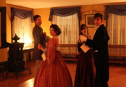 Victorian couples in fancy dress dance by lamplight at a soiree