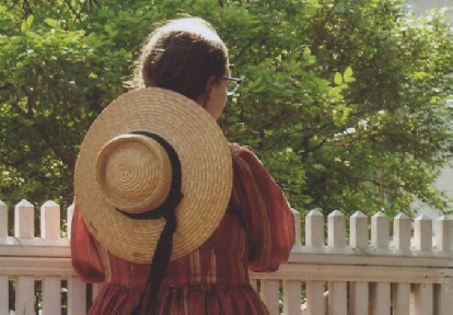 young woman wearing Victorian dress stands with her back turned