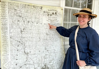 history actor in period costume studies historic map of 19th century Toronto area at Black Creek Pioneer Village