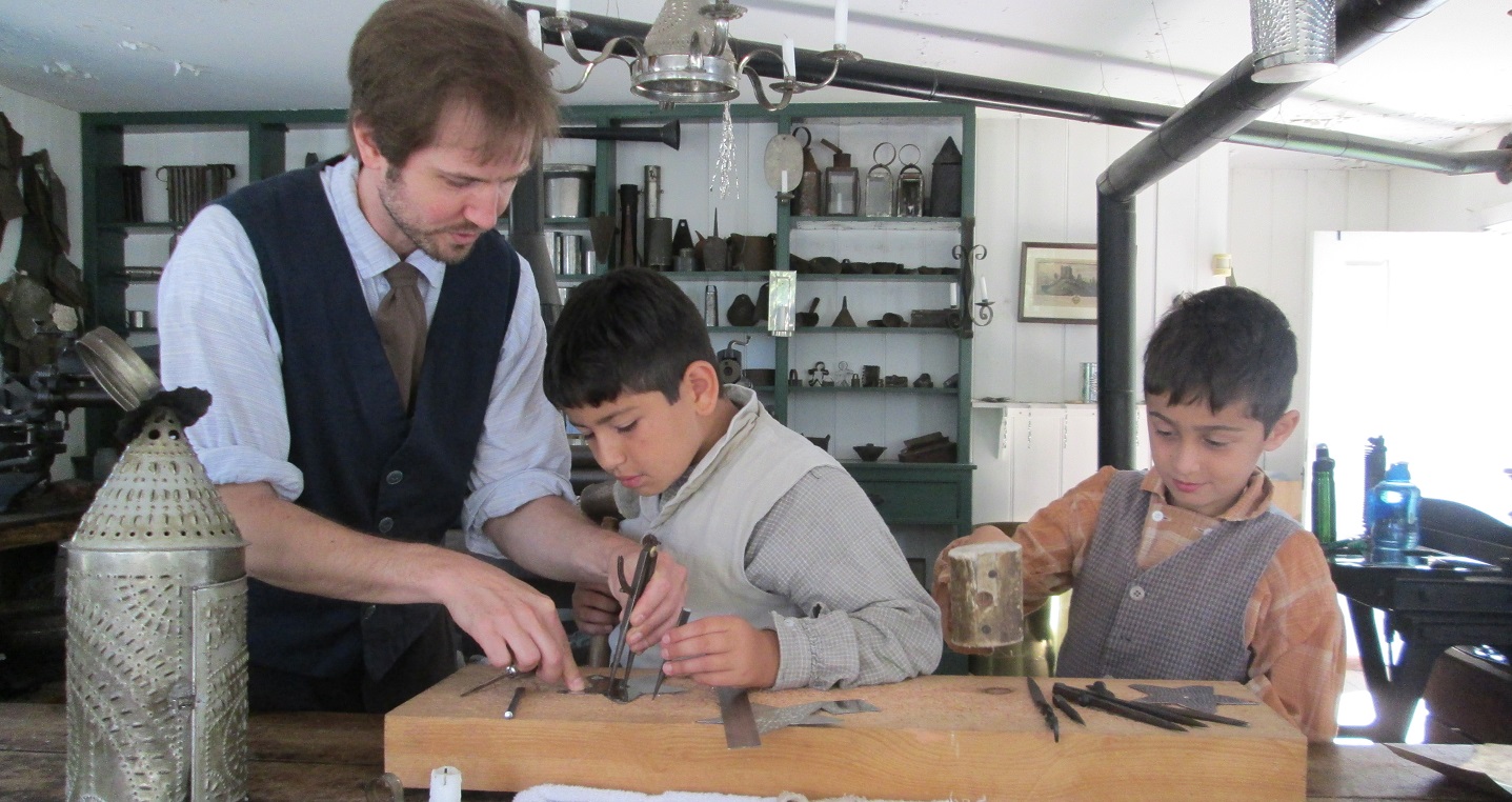 costumed educator demonstrates tinsmithing techniques