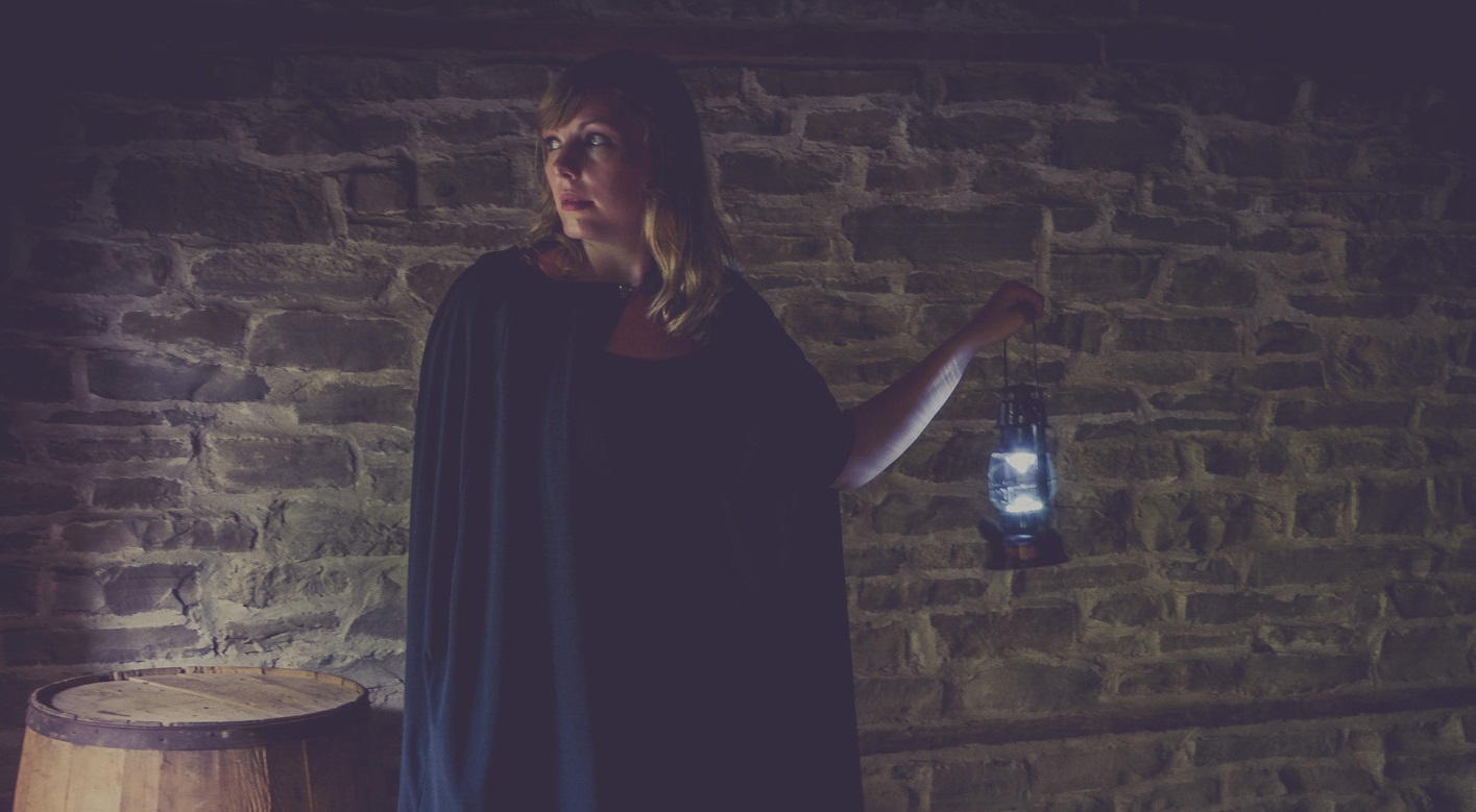 guide with lantern leads a ghost tour of  Black Creek Pioneer Village at night