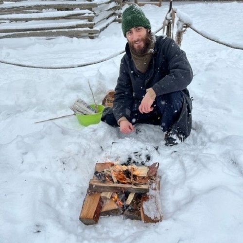 costumed educator demonstrates traditional method of fire making