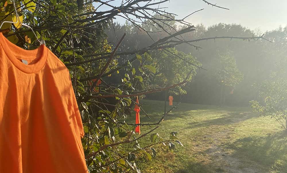 Orange shirts on trees alongside a trail